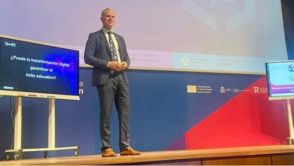 Jeff Lowe, SMART Technologies EVP and Chief Commercial Officer, presenting on stage at a conference about digital transformation in education with a SMART interactive display showing a question in Spanish.