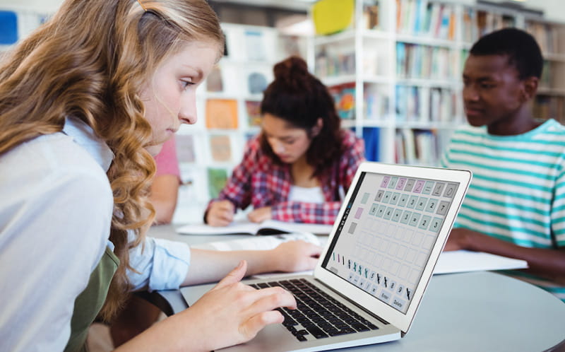 Student focused on practicing with a laptop in a classroom, illustrating individual learning and application.